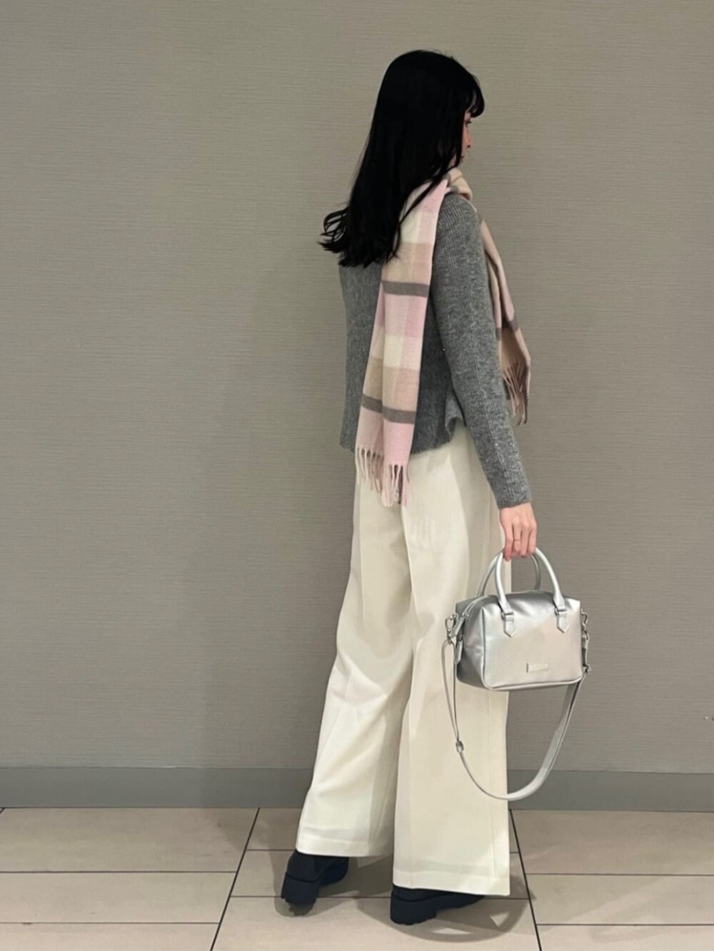 ブラック系のブーツ、シルバー系のボストンバッグ、グレー系のニット/セーターを着用したレディースの秋コーディネートの3枚目の写真