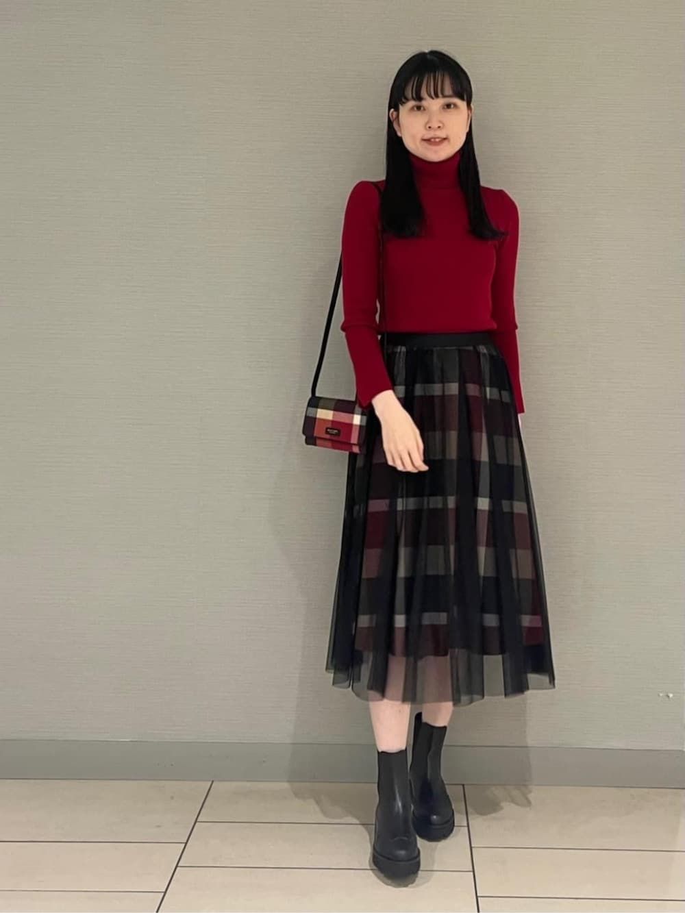ブラック系のブーツ、レッド系のスカート、レッド系のニット/セーターを着用したレディースの秋コーディネートの3枚目の写真