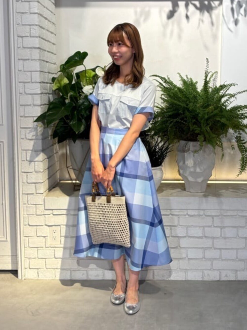 シルバー系のバレエシューズ、ホワイト系のトートバッグ、ブルー系のシャツ/ブラウスを着用したレディースの夏コーディネートの2枚目の写真