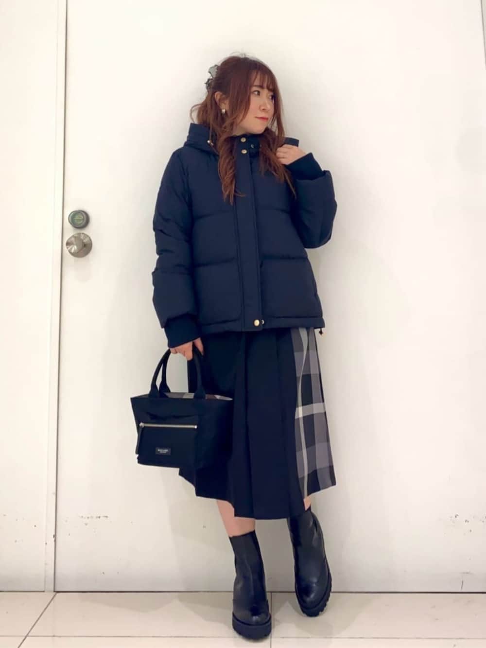 ブラック系のブーツ、ブラック系のハンドバッグ、ブラック系のスカートを着用したレディースの秋コーディネートの3枚目の写真