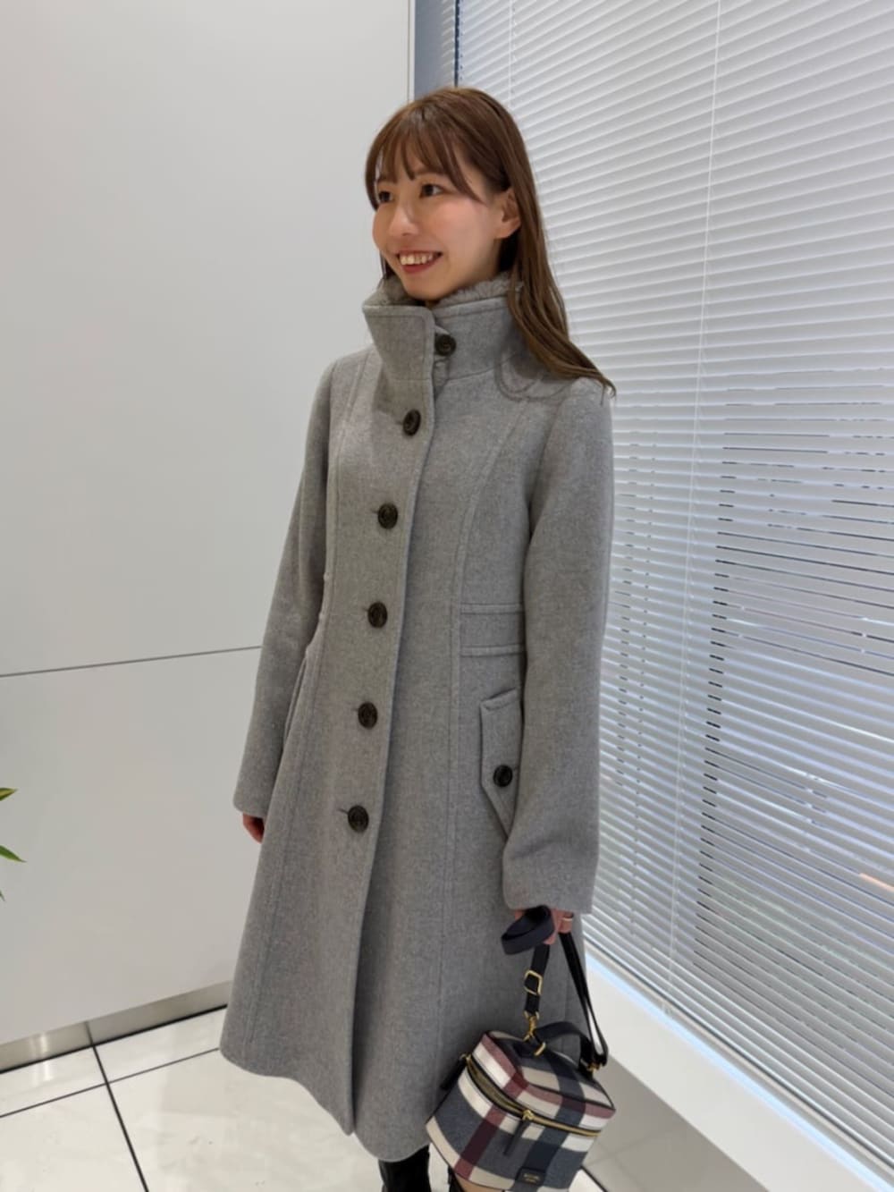 ベージュ系のショルダーバッグ、グレー系のその他アウターを着用したレディースの冬コーディネートの2枚目の写真