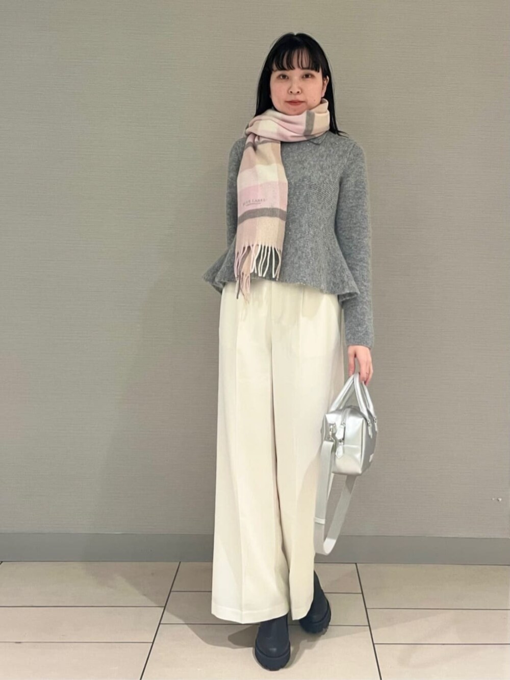 ブラック系のブーツ、シルバー系のボストンバッグ、グレー系のニット/セーターを着用したレディースの秋コーディネートの2枚目の写真