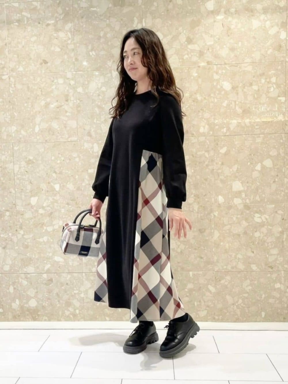 ブラック系のワンピース、ベージュ系のボストンバッグ、ホワイト系のマフラーを着用したレディースの秋コーディネートの2枚目の写真