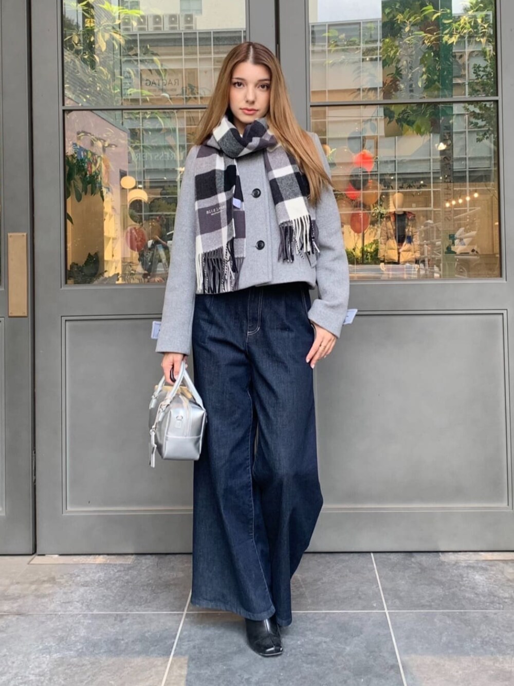 ブルー系のデニムパンツ、シルバー系のボストンバッグ、グレー系のノーカラージャケットを着用したレディースの秋コーディネートの2枚目の写真