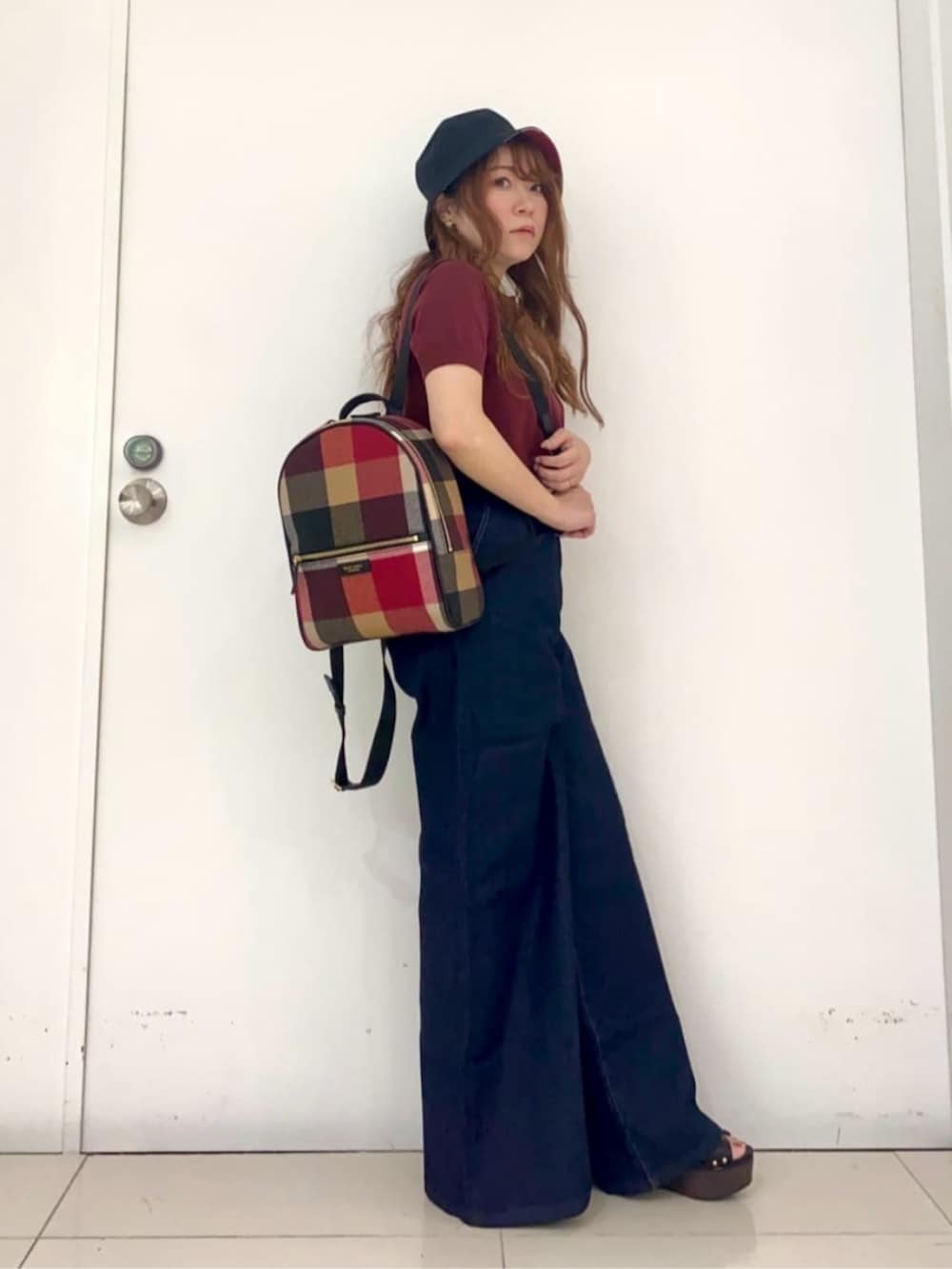 レッド系のバックパック/リュック、ブルー系のデニムパンツ、レッド系のポロシャツを着用したレディースの夏コーディネートの2枚目の写真