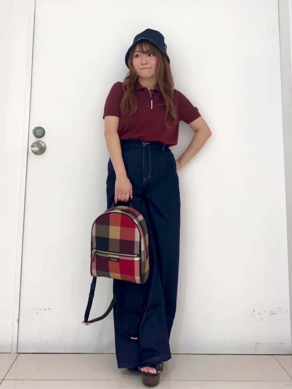 レッド系のバックパック/リュック、ブルー系のデニムパンツ、レッド系のポロシャツを着用したレディースの夏コーディネートの3枚目の写真