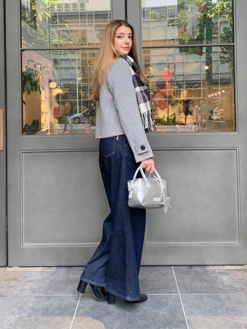 ブルー系のデニムパンツ、シルバー系のボストンバッグ、グレー系のノーカラージャケットを着用したレディースの秋コーディネートの3枚目の写真