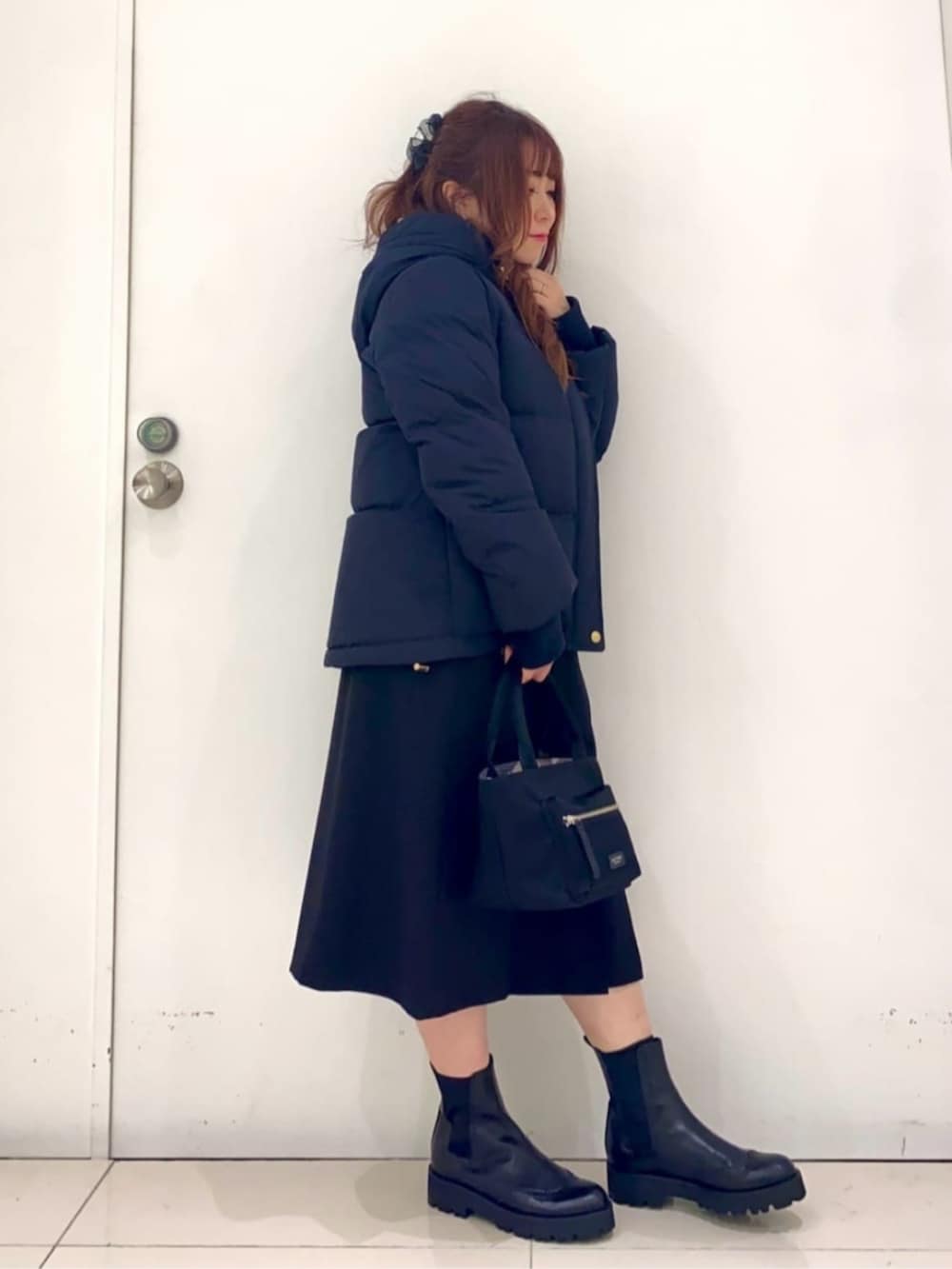 ブラック系のブーツ、ブラック系のハンドバッグ、ブラック系のスカートを着用したレディースの秋コーディネートの2枚目の写真