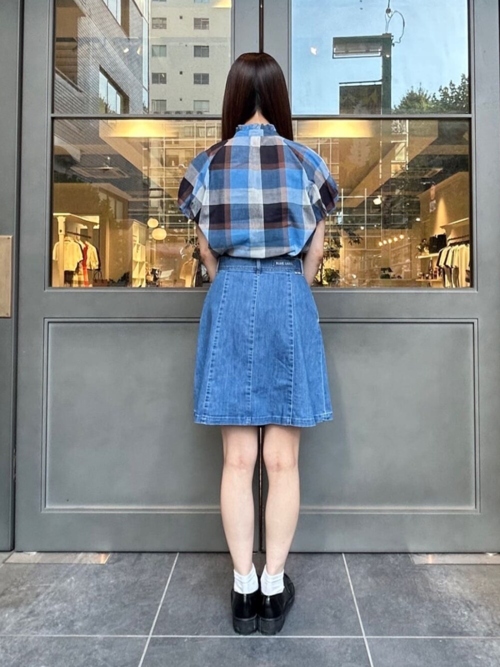 ブラック系のローファー、ブルー系のショルダーバッグ、ブルー系のデニムスカートを着用したレディースの夏コーディネートの3枚目の写真