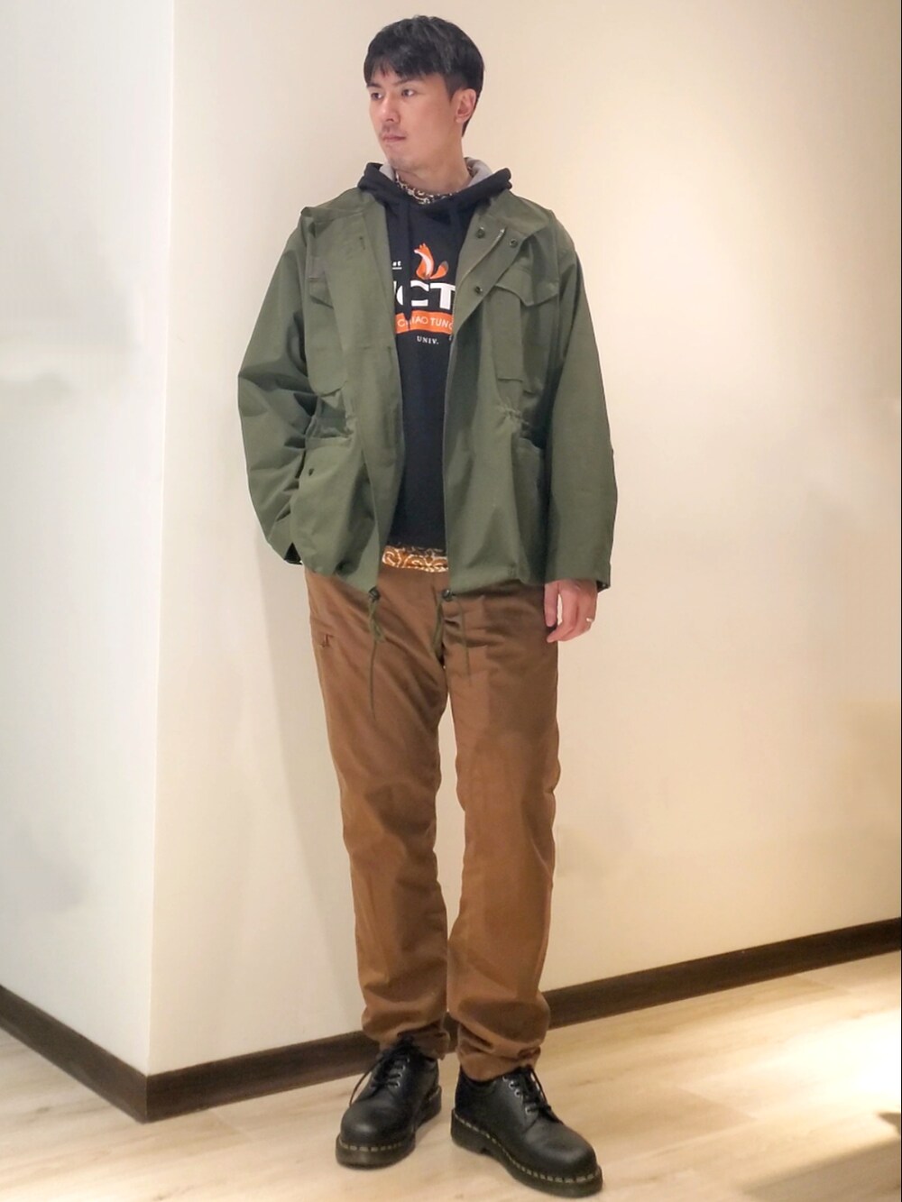 ブラウン系のその他パンツ、ブラック系のドレスシューズ、グリーン系のミリタリージャケットを着用したメンズの冬コーディネートの2枚目の写真