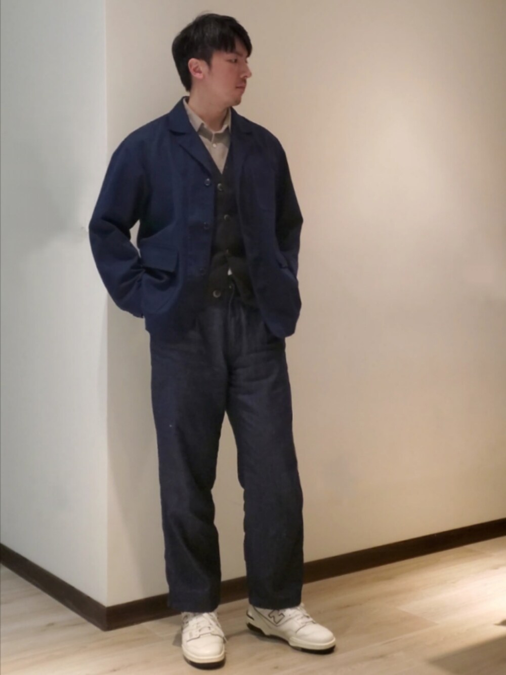 ブルー系のデニムパンツ、ホワイト系のスニーカー、グレー系のベストを着用したメンズの秋コーディネートの2枚目の写真