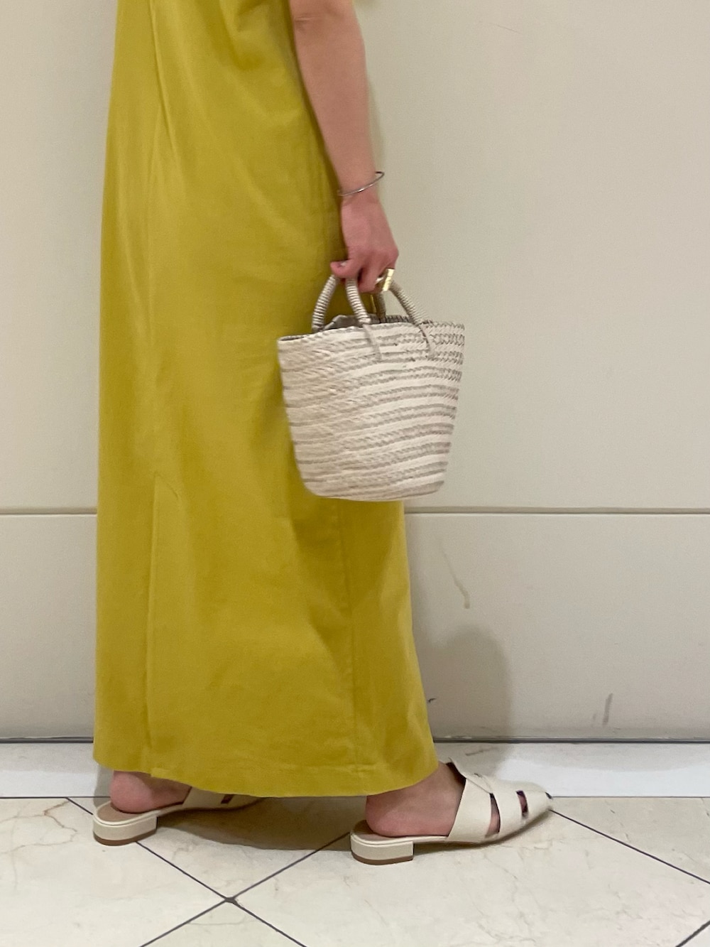 イエロー系のワンピース、ホワイト系のサンダル、ホワイト系のバッグを着用したレディースの春コーディネートの4枚目の写真