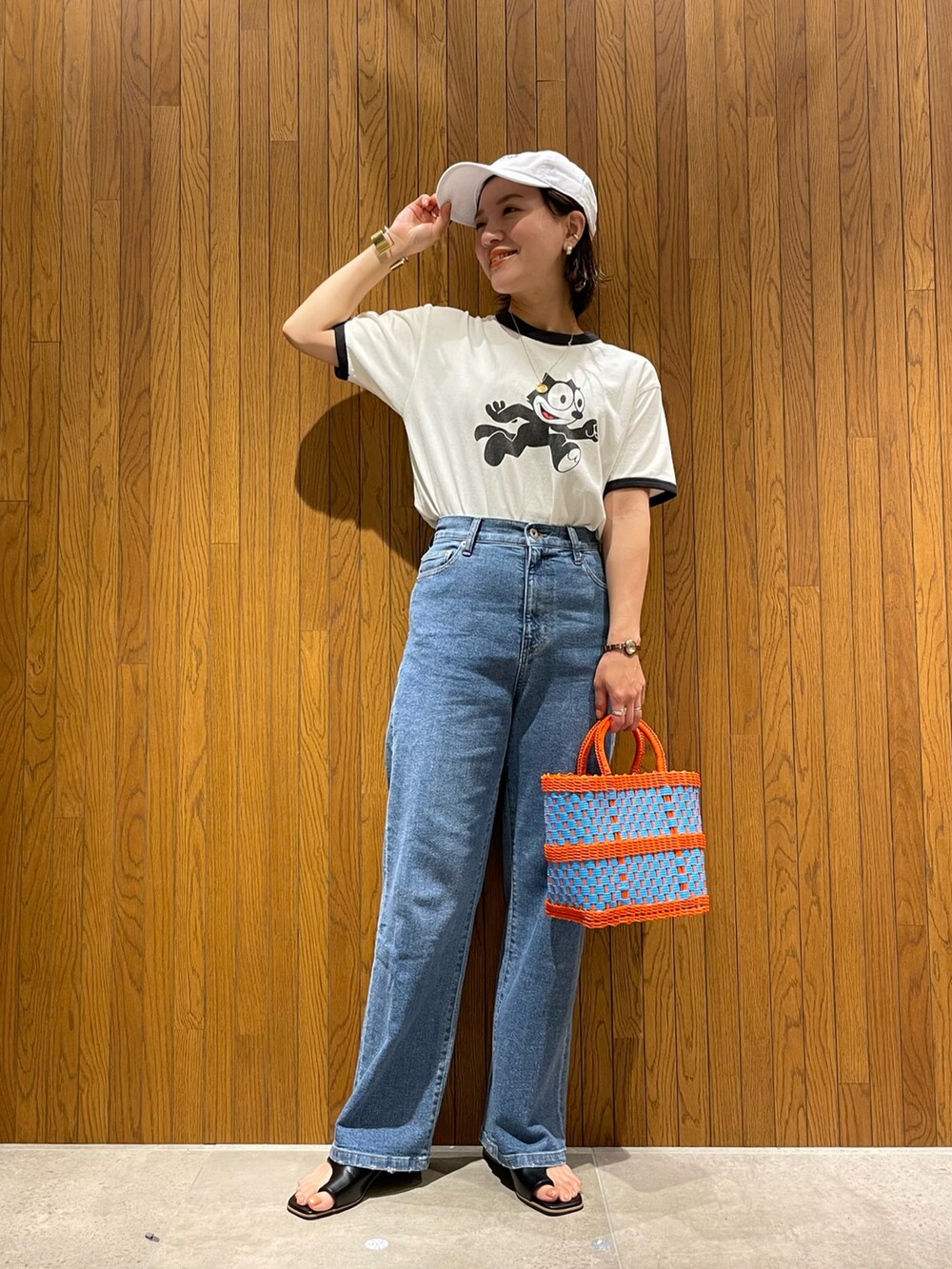 ホワイト系のTシャツ/カットソー、オレンジ系のハンドバッグ、ブルー系のデニムパンツを着用したレディースの夏コーディネートの2枚目の写真
