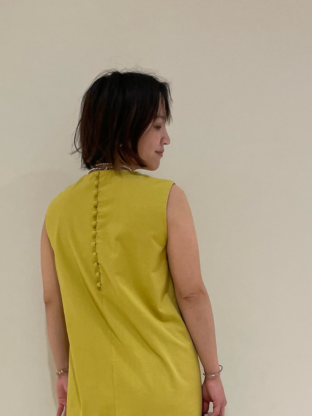 イエロー系のワンピース、ホワイト系のサンダル、ホワイト系のバッグを着用したレディースの春コーディネートの3枚目の写真