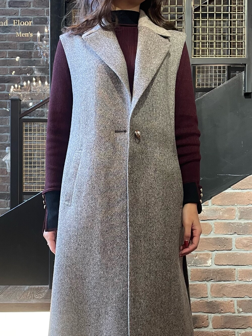 ブラウン系のベスト、レッド系のワンピースを着用したレディースの冬コーディネートの2枚目の写真