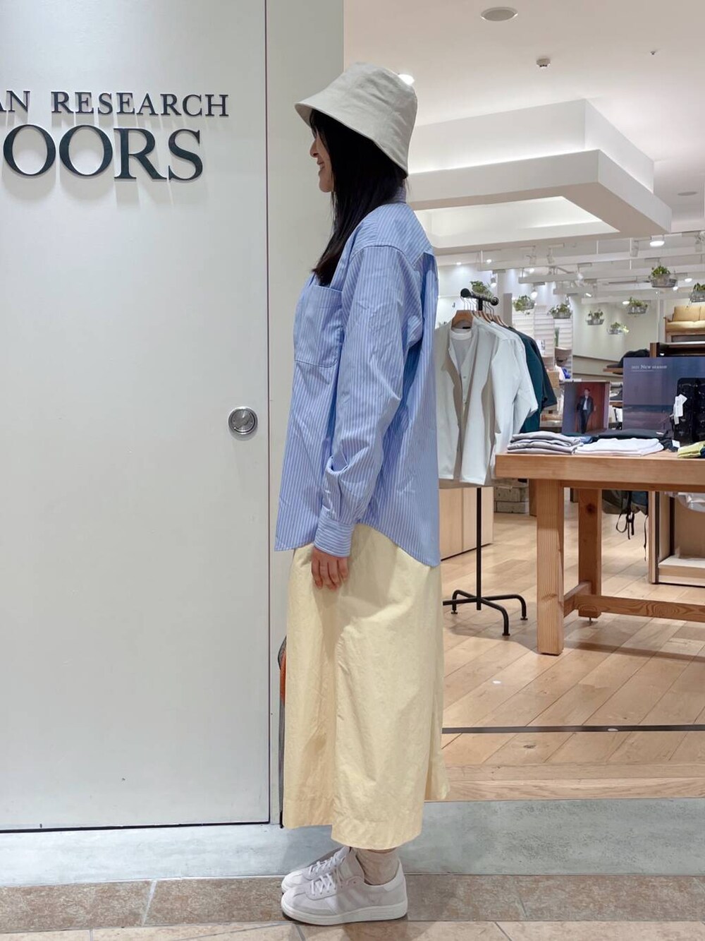 イエロー系のスカート、ブルー系のシャツ/ブラウス、ホワイト系のスニーカーを着用したレディースの春コーディネートの3枚目の写真
