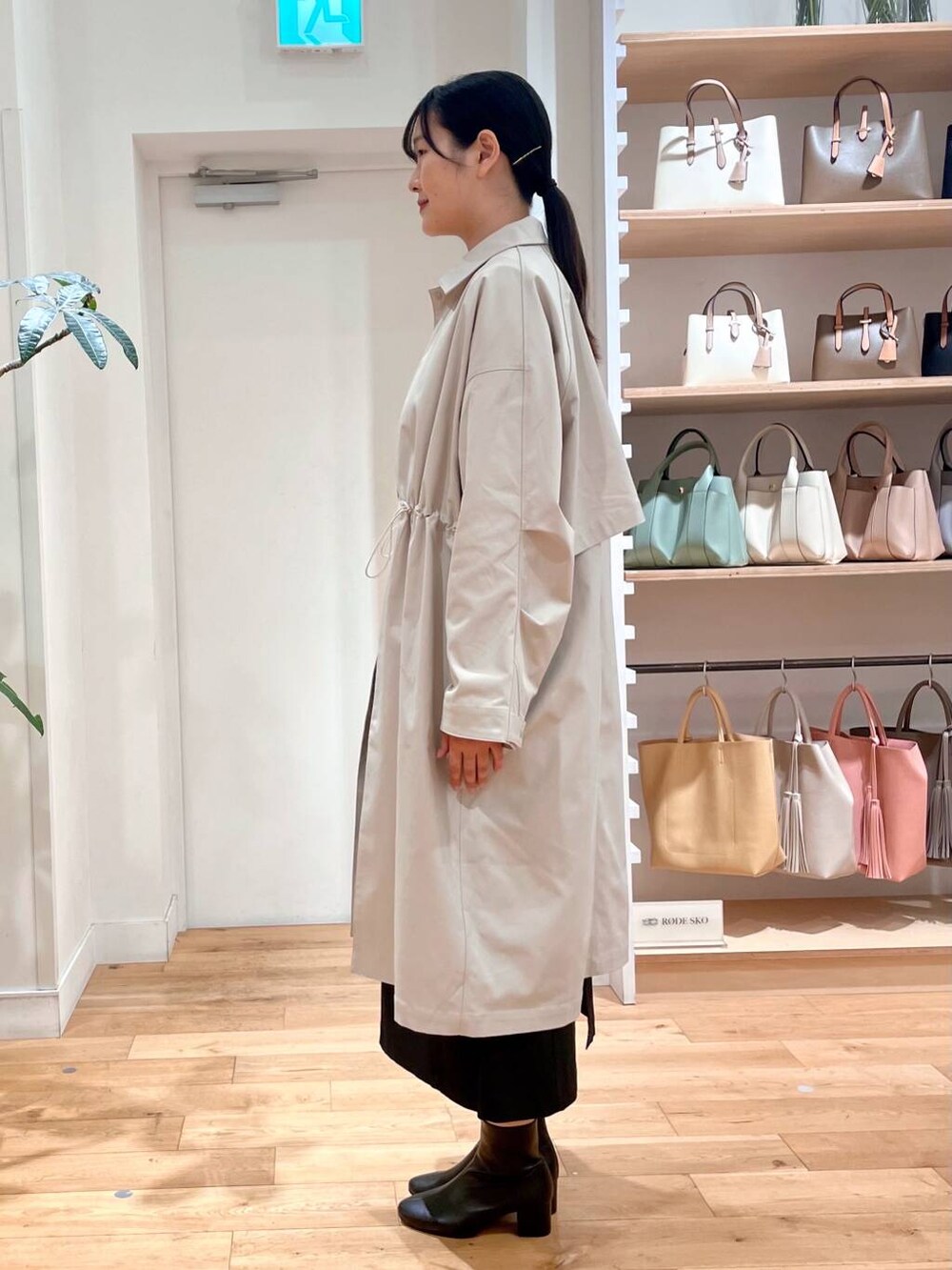 ブラック系のブーツ、イエロー系のニット/セーター、ブラック系のジャンパースカートを着用したレディースの春コーディネートの4枚目の写真