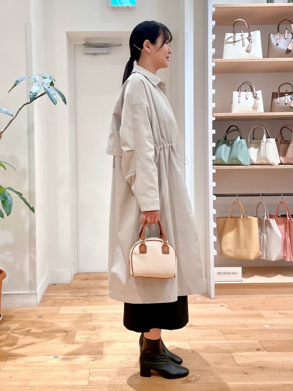 ブラック系のブーツ、イエロー系のニット/セーター、ブラック系のジャンパースカートを着用したレディースの春コーディネートの3枚目の写真