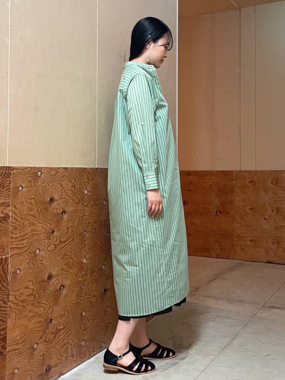 ベージュ系のハンドバッグ、ブラック系のサンダル、グリーン系のワンピースを着用したレディースの春コーディネートの2枚目の写真