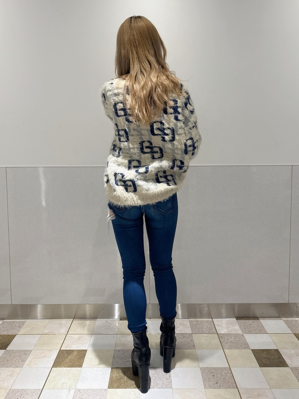 ホワイト系のニット/セーター、ブルー系のデニムパンツ、ブラック系のブーツを着用したレディースの冬コーディネートの3枚目の写真