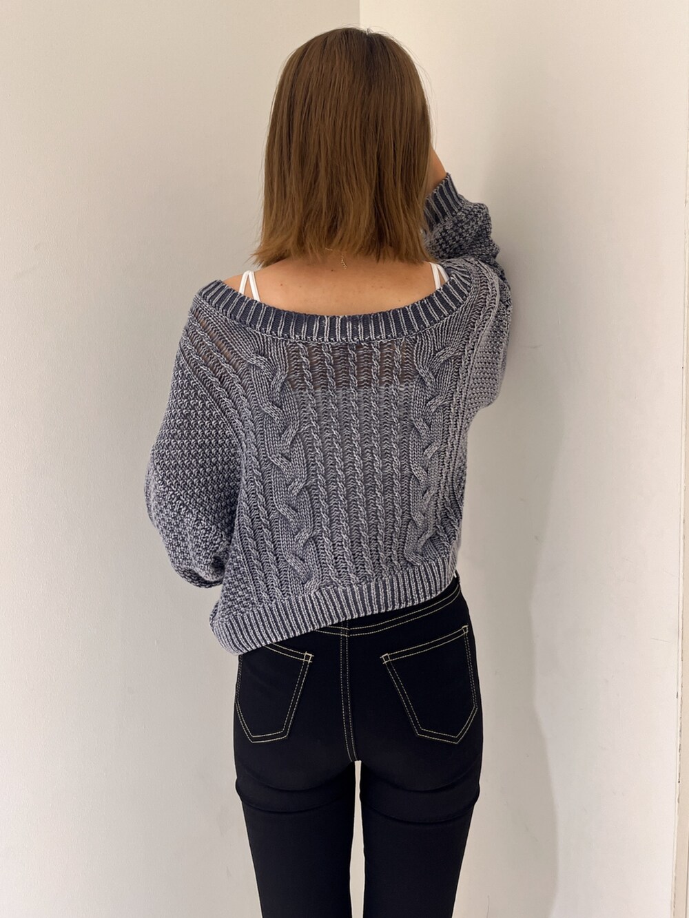 ブルー系のニット/セーター、ホワイト系のキャミソール、ブラック系のデニムパンツを着用したレディースの秋コーディネートの5枚目の写真