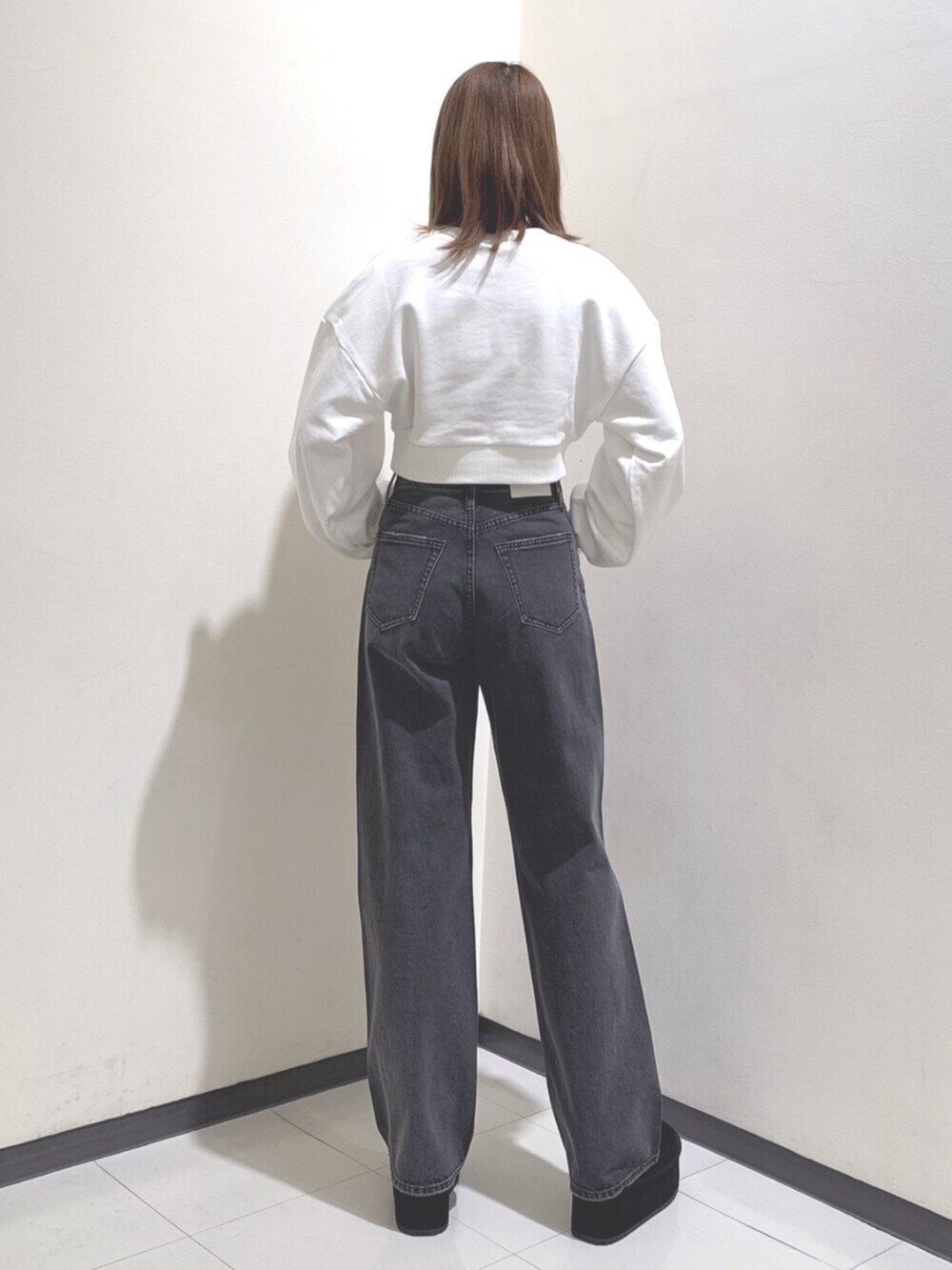 ホワイト系のスウェット、ブラック系のデニムパンツ、ブラック系のブーツを着用したレディースの冬コーディネートの3枚目の写真