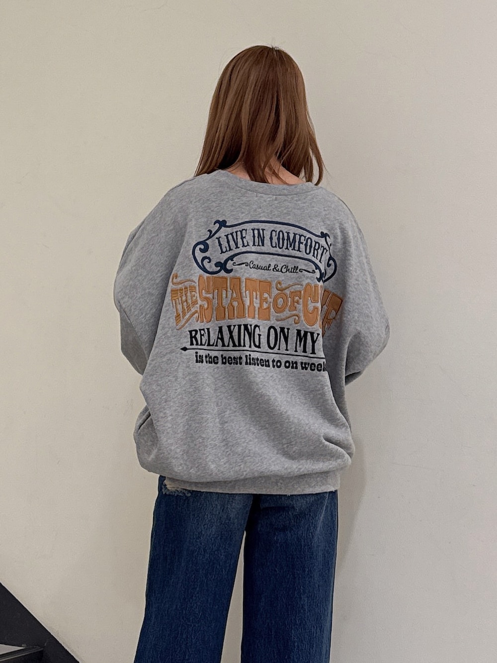 グレー系のスウェット、ブルー系のデニムパンツ、ベージュ系のブーツを着用したレディースの冬コーディネートの5枚目の写真