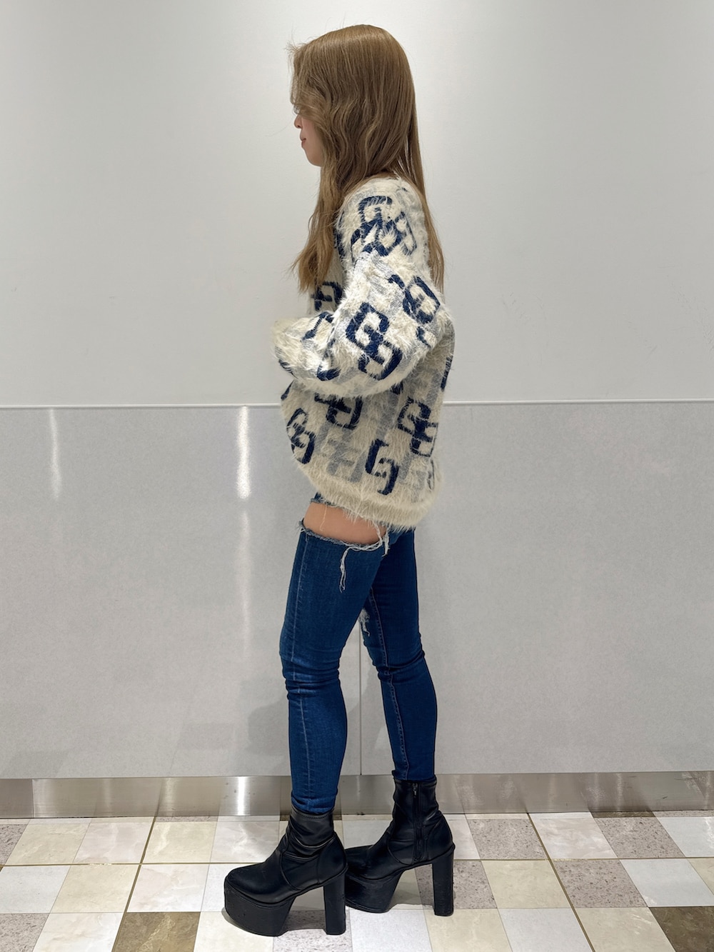 ホワイト系のニット/セーター、ブルー系のデニムパンツ、ブラック系のブーツを着用したレディースの冬コーディネートの2枚目の写真