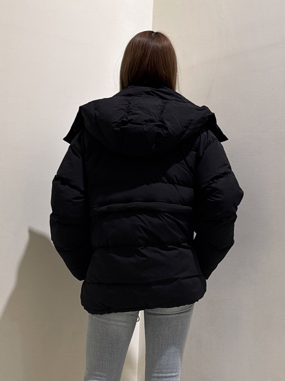 ブラック系のダウンジャケット/コート、グレー系のニット/セーター、ブルー系のデニムパンツを着用したレディースの冬コーディネートの5枚目の写真