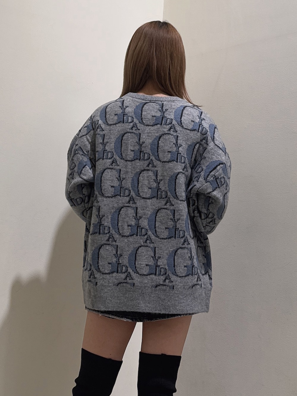 グレー系のニット/セーター、ブラック系のデニムスカート、ブラック系のブーツを着用したレディースの冬コーディネートの5枚目の写真