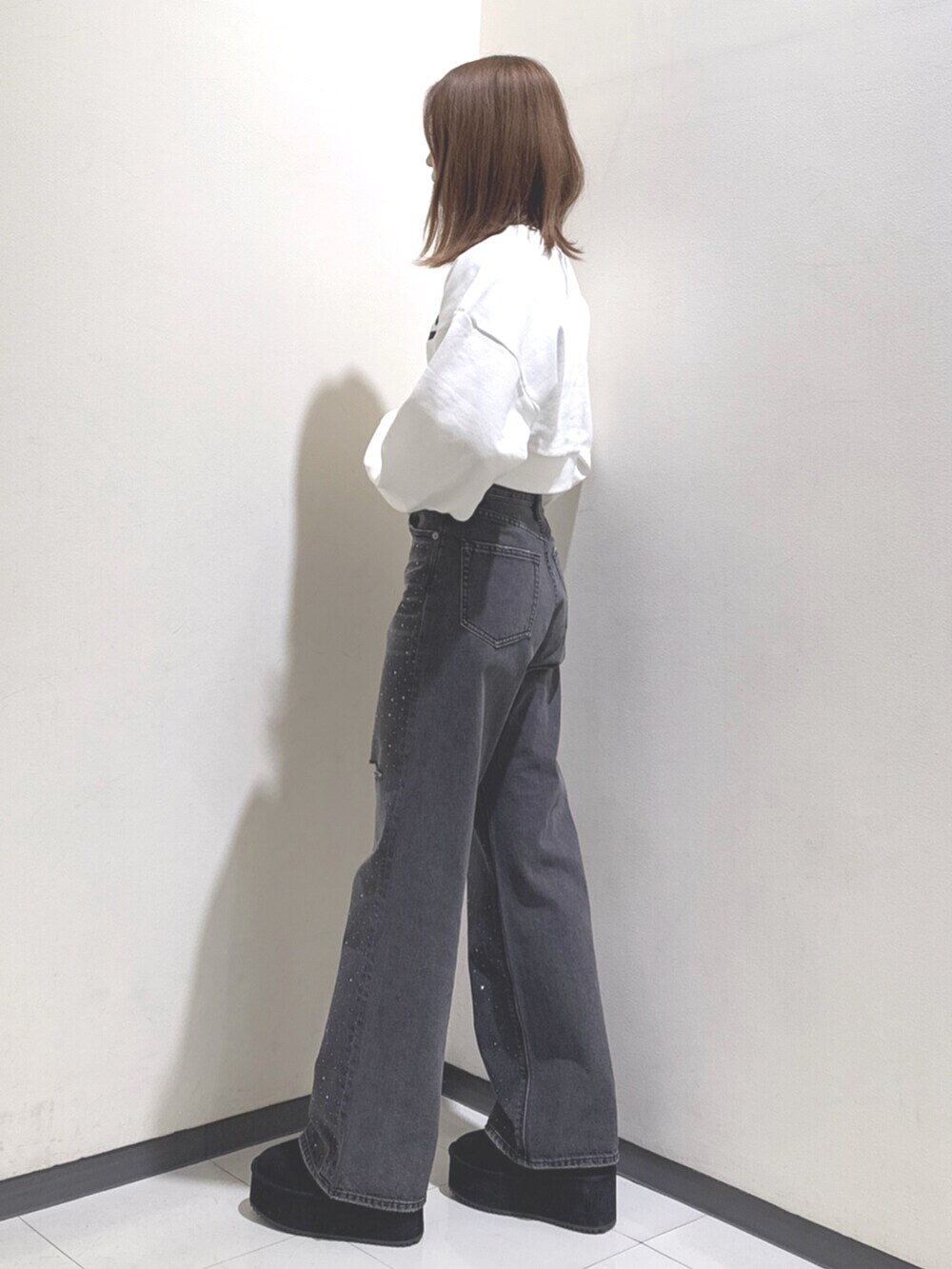 ホワイト系のスウェット、ブラック系のデニムパンツ、ブラック系のブーツを着用したレディースの冬コーディネートの2枚目の写真