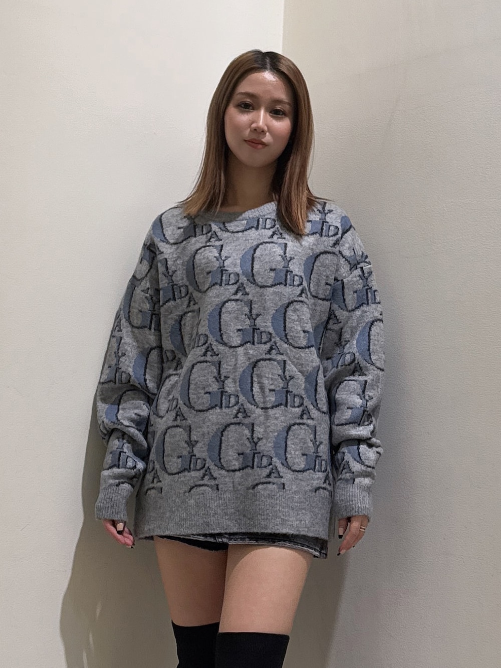 グレー系のニット/セーター、ブラック系のデニムスカート、ブラック系のブーツを着用したレディースの冬コーディネートの4枚目の写真