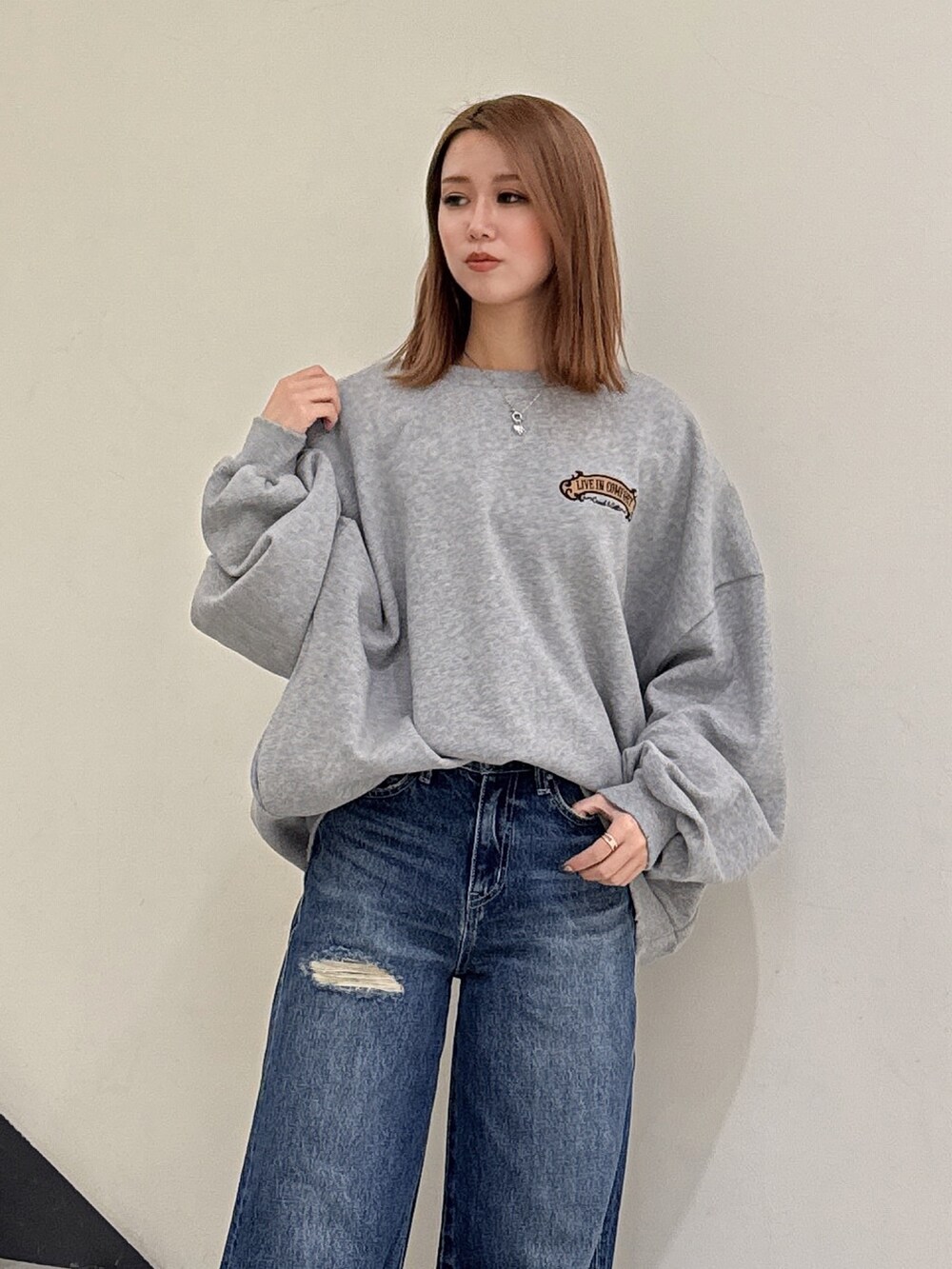 グレー系のスウェット、ブルー系のデニムパンツ、ベージュ系のブーツを着用したレディースの冬コーディネートの4枚目の写真