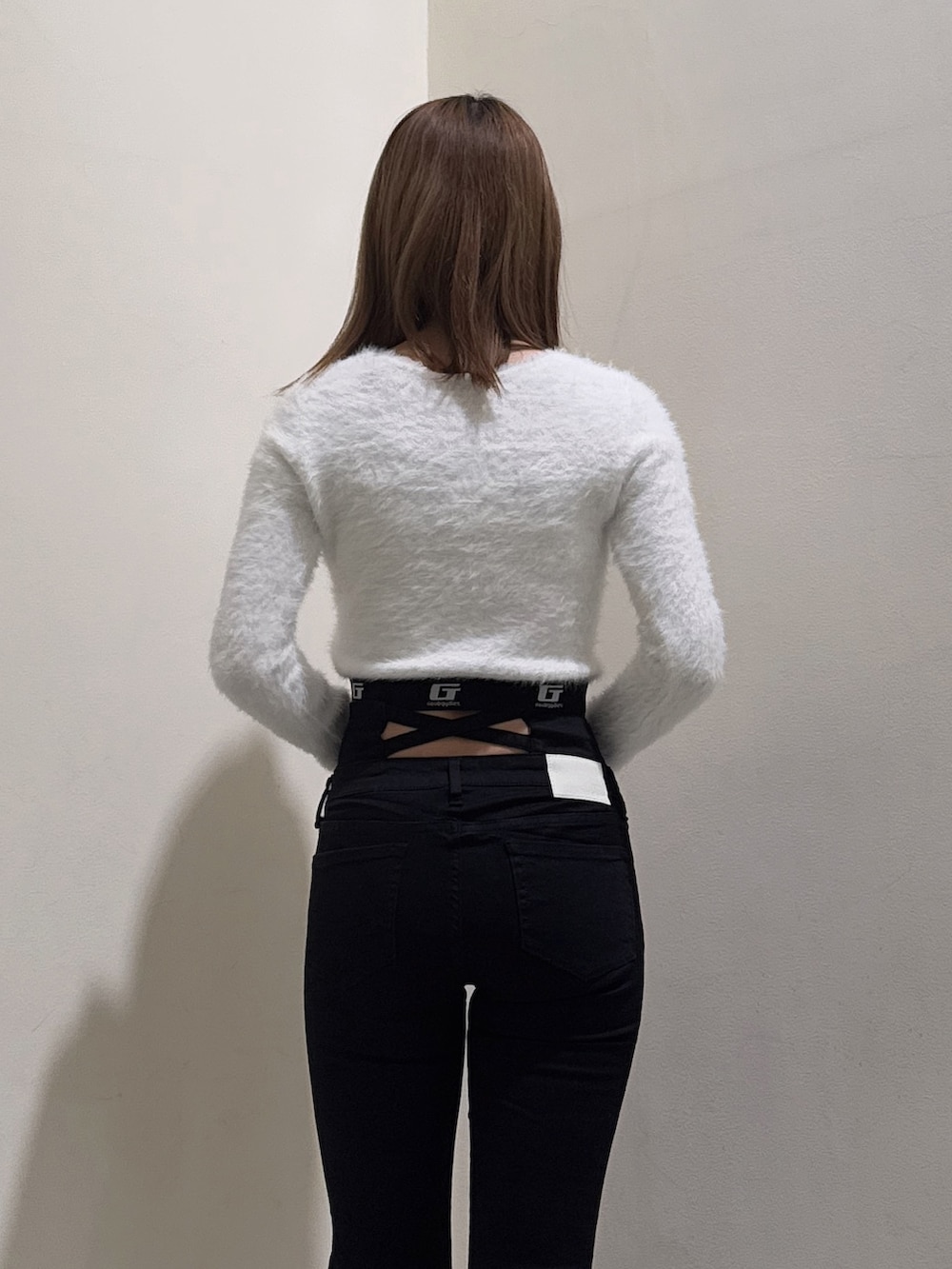 ホワイト系のニット/セーター、ブラック系のデニムパンツ、ブラック系のブーツを着用したレディースの冬コーディネートの5枚目の写真