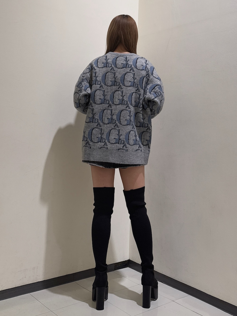 グレー系のニット/セーター、ブラック系のデニムスカート、ブラック系のブーツを着用したレディースの冬コーディネートの3枚目の写真