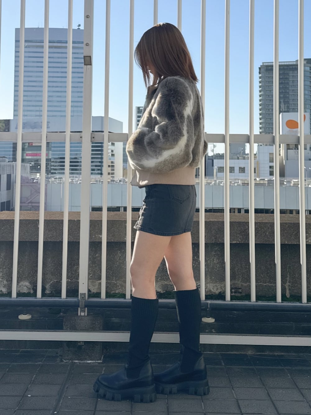 その他のその他アウター、ホワイト系のニット/セーター、ブラック系のデニムスカートを着用したレディースの冬コーディネートの2枚目の写真