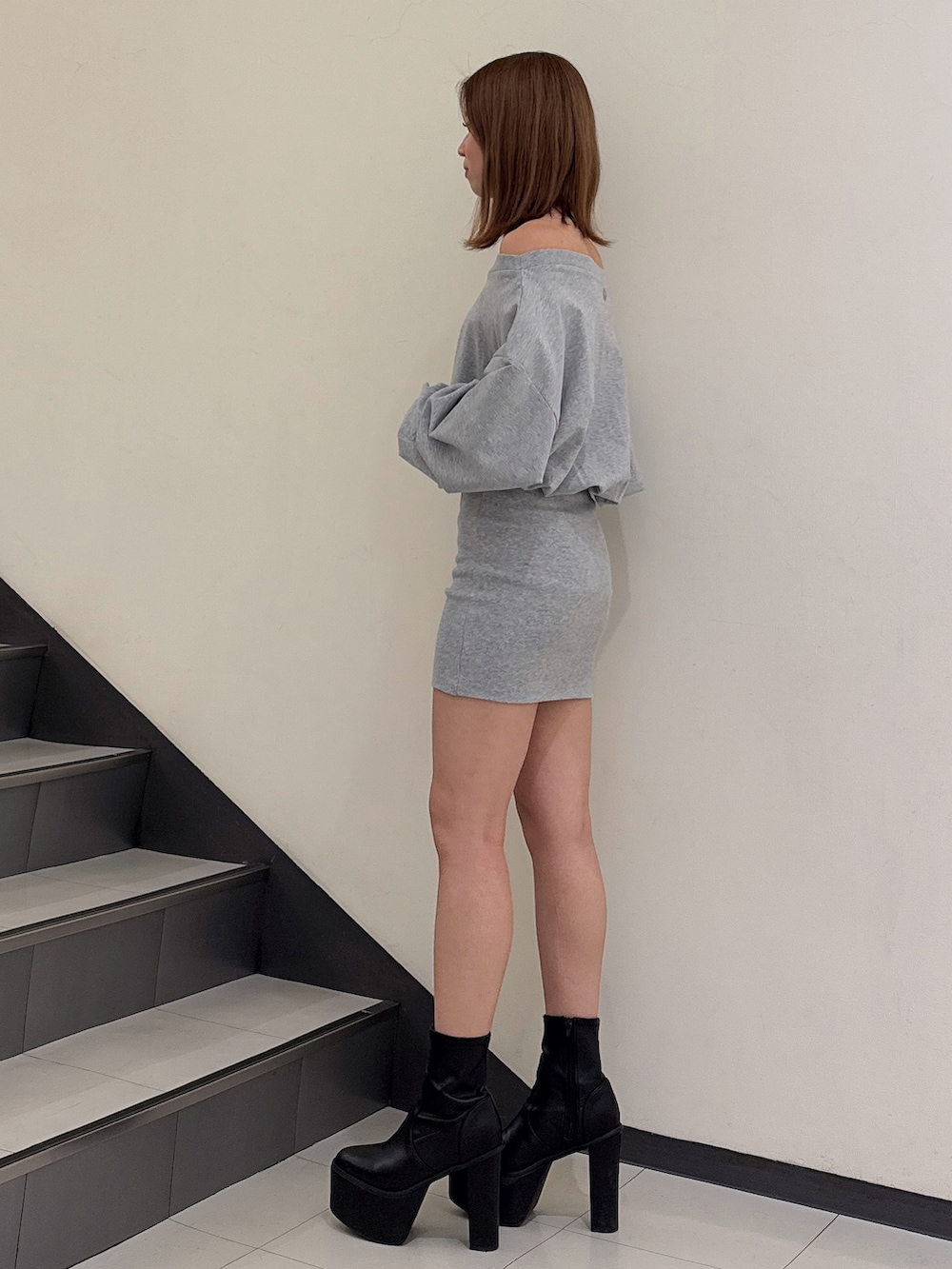 グレー系のワンピース、ブラック系のブーツを着用したレディースの冬コーディネートの2枚目の写真