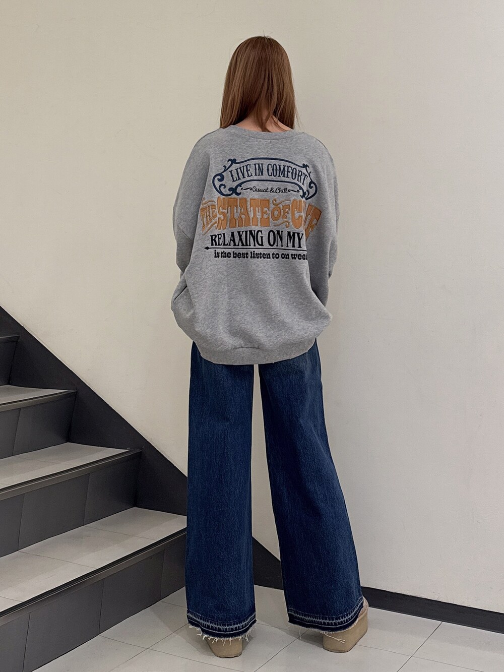 グレー系のスウェット、ブルー系のデニムパンツ、ベージュ系のブーツを着用したレディースの冬コーディネートの3枚目の写真