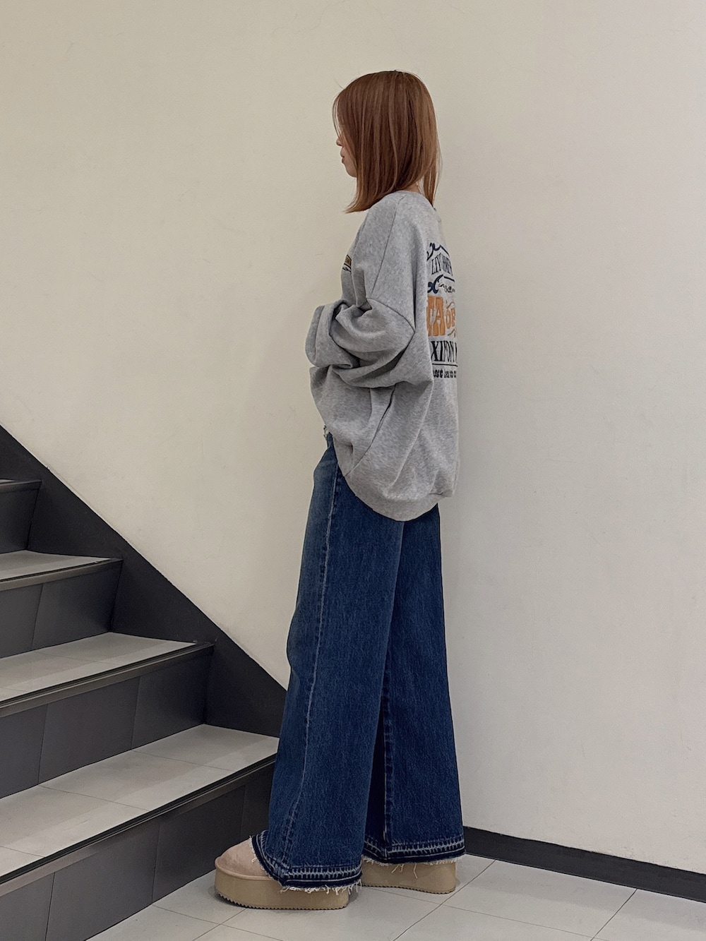 グレー系のスウェット、ブルー系のデニムパンツ、ベージュ系のブーツを着用したレディースの冬コーディネートの2枚目の写真