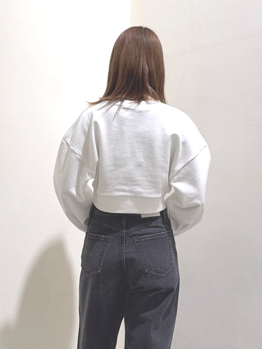 ホワイト系のスウェット、ブラック系のデニムパンツ、ブラック系のブーツを着用したレディースの冬コーディネートの5枚目の写真