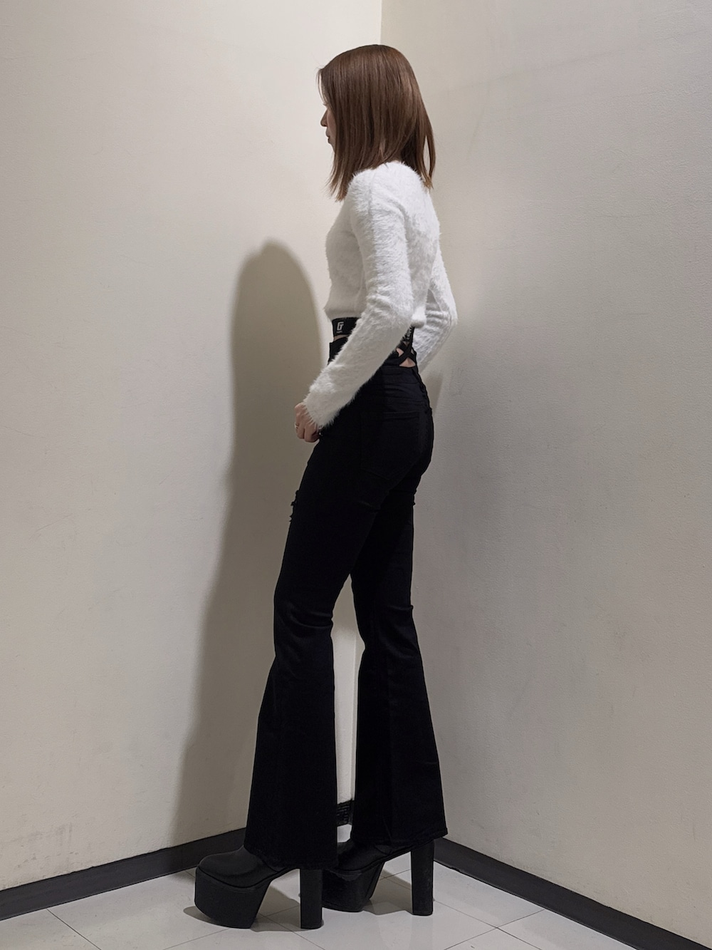 ホワイト系のニット/セーター、ブラック系のデニムパンツ、ブラック系のブーツを着用したレディースの冬コーディネートの2枚目の写真