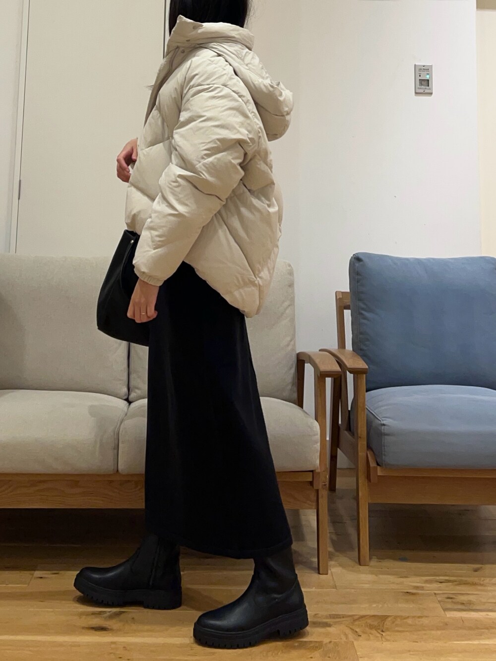 ホワイト系のダウンジャケット/コート、グリーン系のニット/セーター、ブラック系のスカートを着用したレディースの冬コーディネートの2枚目の写真