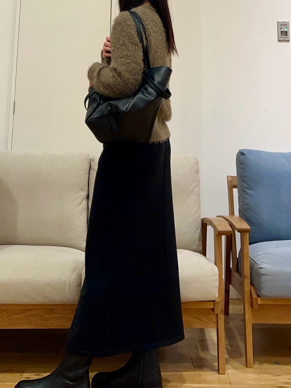 ホワイト系のダウンジャケット/コート、グリーン系のニット/セーター、ブラック系のスカートを着用したレディースの冬コーディネートの6枚目の写真