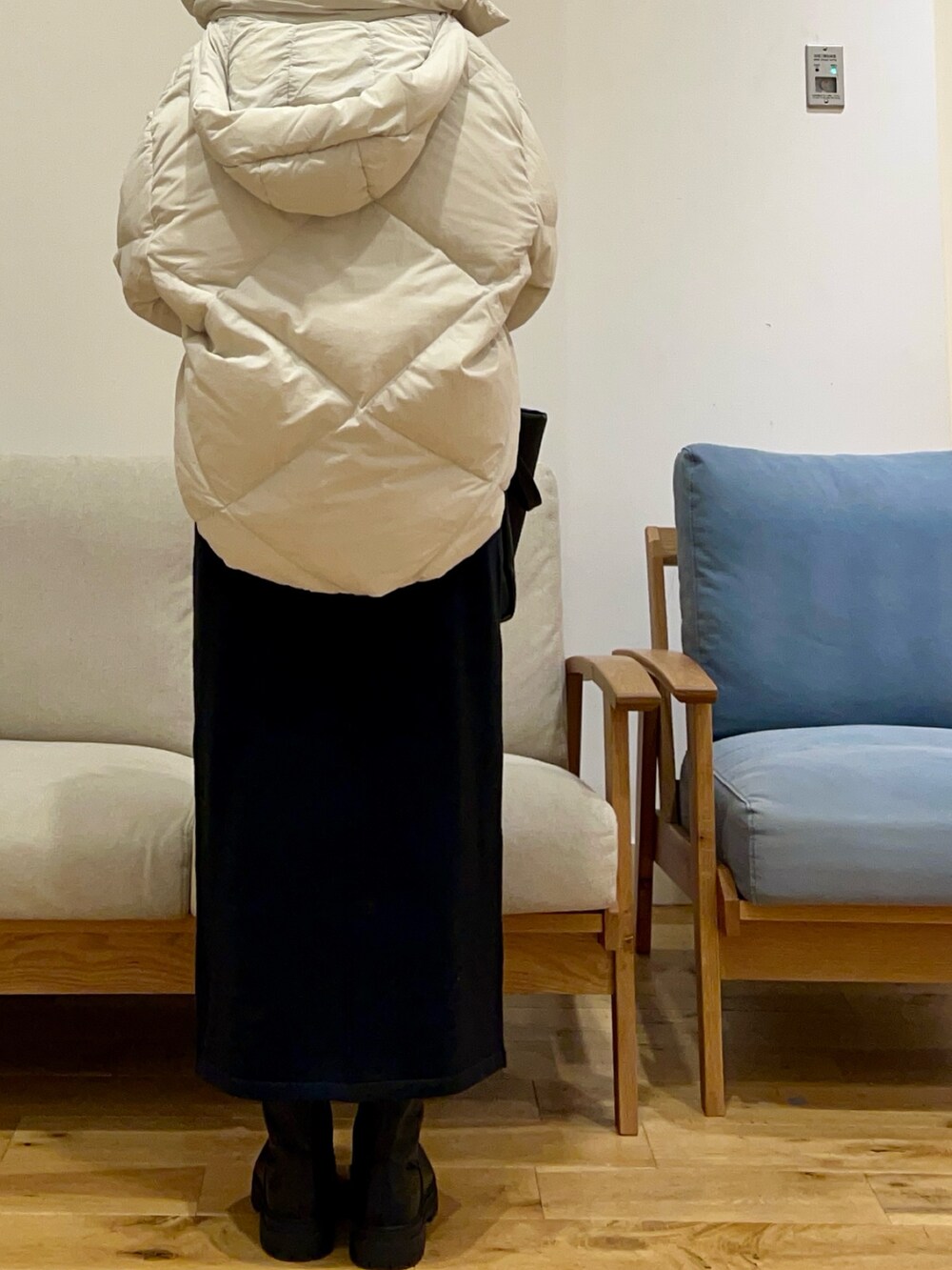 ホワイト系のダウンジャケット/コート、グリーン系のニット/セーター、ブラック系のスカートを着用したレディースの冬コーディネートの3枚目の写真