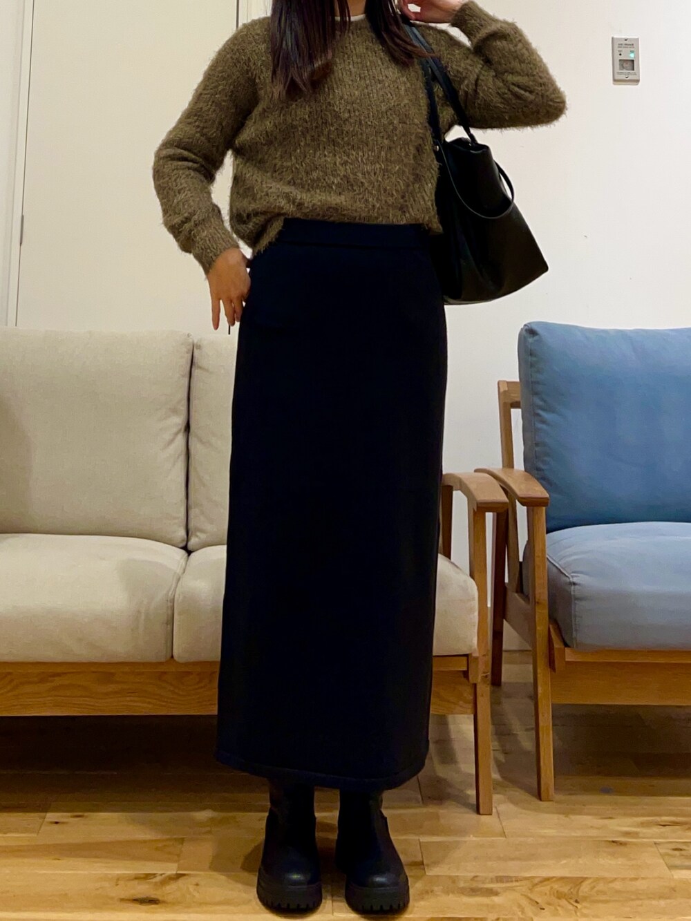 ホワイト系のダウンジャケット/コート、グリーン系のニット/セーター、ブラック系のスカートを着用したレディースの冬コーディネートの5枚目の写真