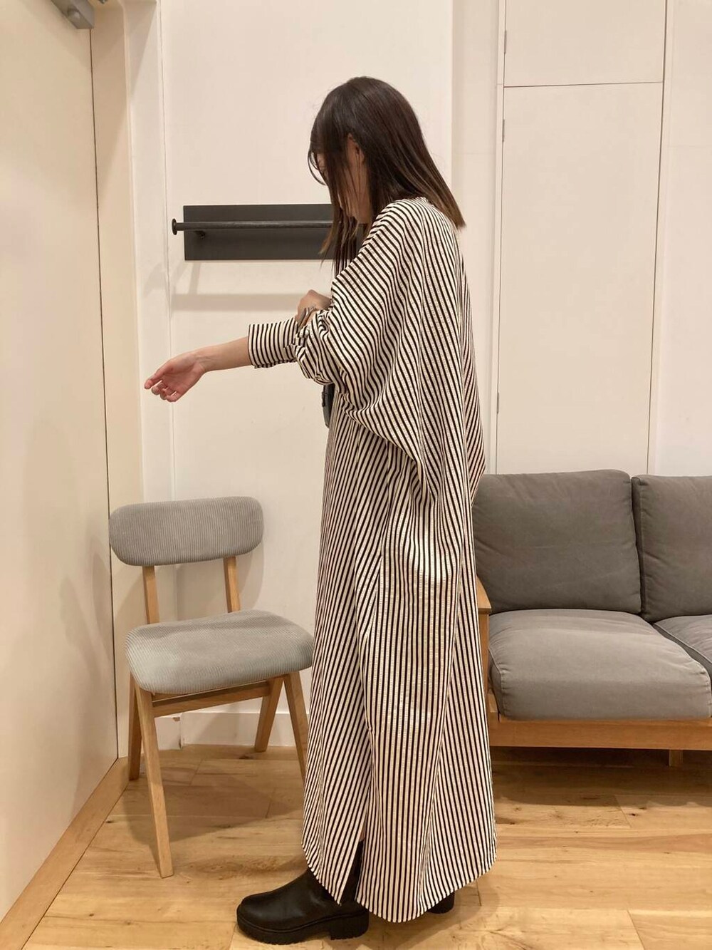 ブラック系のブーツ、ブラック系のボストンバッグ、ベージュ系のワンピースを着用したレディースの秋コーディネートの2枚目の写真