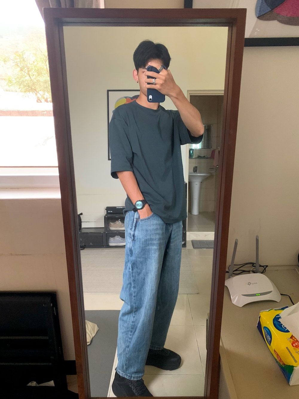 ブラック系のパーカー、ブルー系のデニムパンツ、ブラック系のスニーカーを着用したメンズの秋コーディネートの2枚目の写真