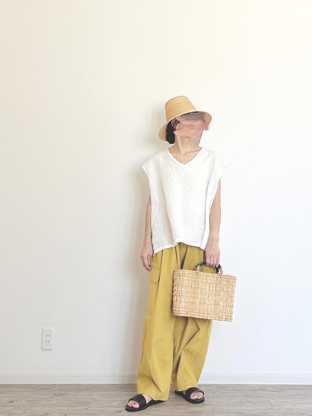 ベージュ系のかごバッグ、イエロー系のカーゴパンツ、ブラウン系のサンダルを着用したレディースの夏コーディネートの2枚目の写真