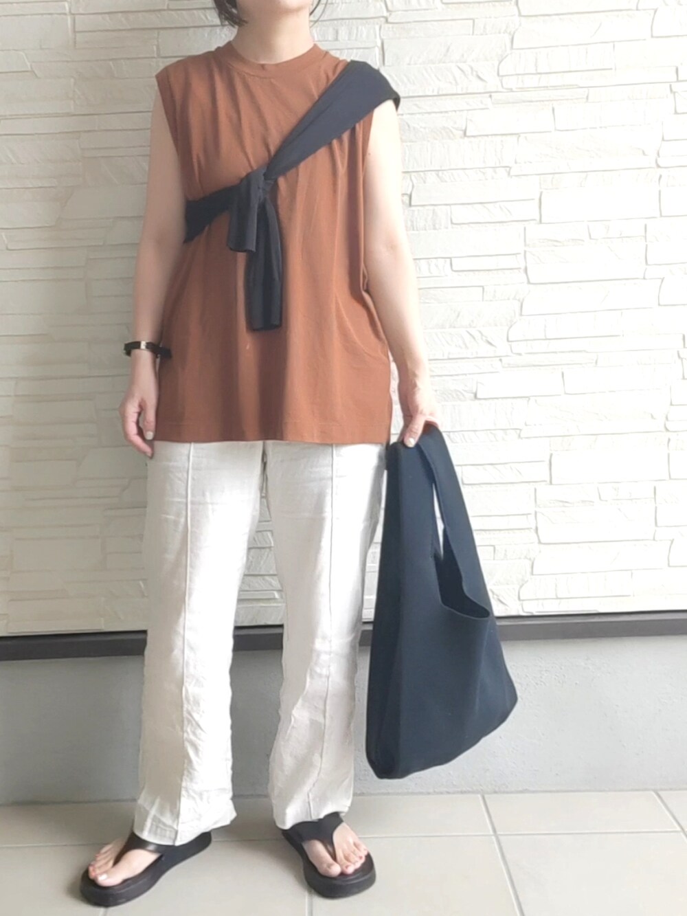 ホワイト系のトートバッグ、ブラック系のサンダルを着用したレディースの夏コーディネートの2枚目の写真