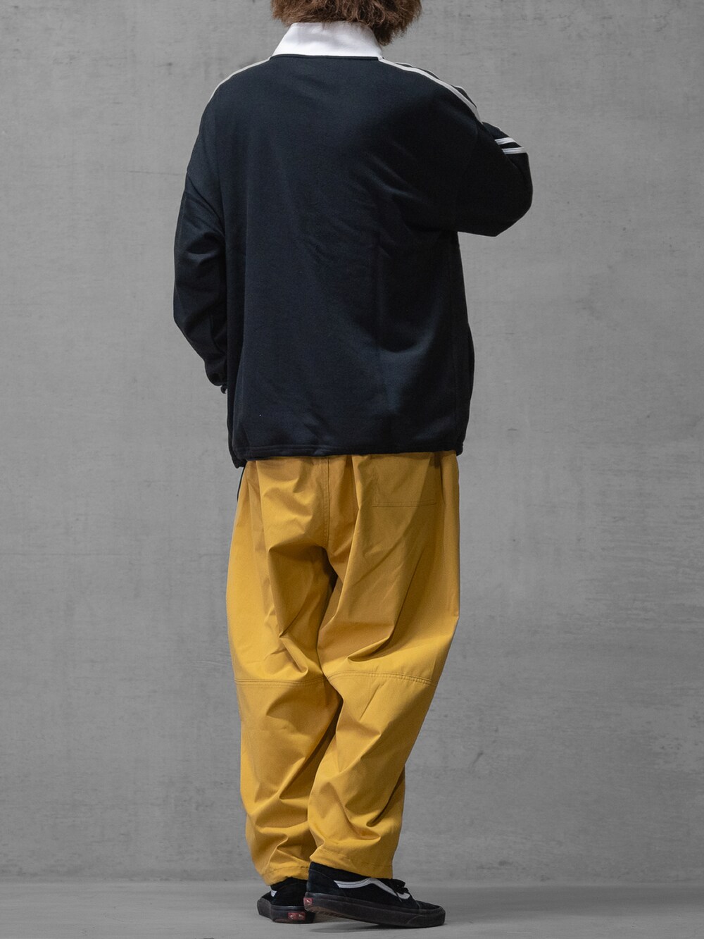 イエロー系のスラックス、ブラック系のスニーカー、ホワイト系のスウェットを着用したメンズの春コーディネートの3枚目の写真